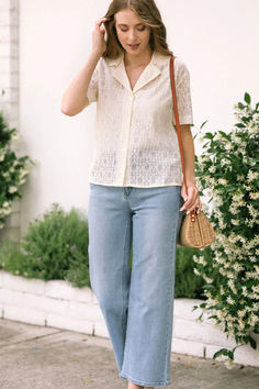 a woman walking down the street talking on her cell phone and holding a straw bag