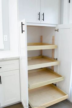 an empty pantry with white cabinets and wood shelves