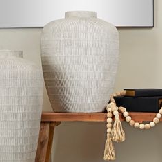 a white vase sitting on top of a wooden table next to a black book bag