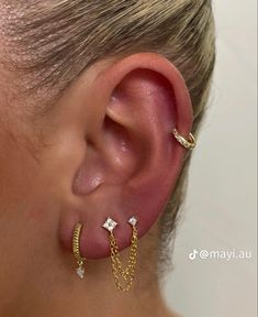 a woman wearing three different types of ear piercings