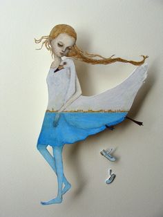 a paper sculpture of a woman with long red hair and blue dress, sitting on top of a white wall