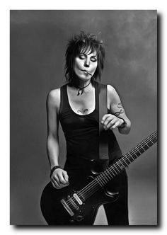 black and white photograph of a woman with an electric guitar in front of her face