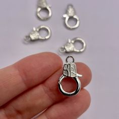 a hand is holding some tiny silver charms