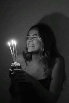 a woman holding a cupcake with candles in it