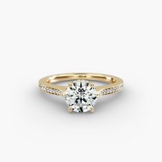 a yellow gold engagement ring with a round diamond in the center and pave set shoulders