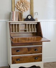 an old wooden desk with three drawers and a clock on the wall above it,