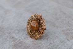 This round brooch in an ornate gold tone frame is perfect for brides or bridesmaids. It measures 1 3/4 in diameter and the clasp closes securely. The brooch/pin is vintage and can compliment any outfit. It can be used for jacket, dress, scarf, wedding jewelry or hat pin. To view my complete Brooch Collection, visit: https://www.etsy.com/shop/AleksJewelry?ref=hdr_shop_menu&section_id=18825972 Search for my entire Shop Collection visit: https://www.etsy.com/shop/AleksJewelry Gold Brooches With Intricate Design For Wedding, Victorian Gold Brooch For Wedding, Brass Brooch For Wedding, Brass Brooch Jewelry For Wedding, Antique Gold Brooches For Wedding, Brass Wedding Brooch, Victorian Gold Wedding Brooch, Gold Brooch Jewelry For Wedding, Gold Wedding Brooch Jewelry