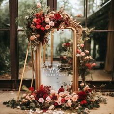 an ornate mirror decorated with flowers and greenery sits in front of a large window