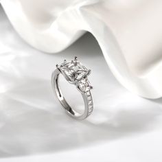 a white gold ring with three princess cut diamonds