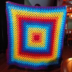 a colorful crocheted blanket sitting on top of a wooden table