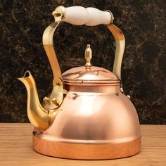 a gold tea kettle sitting on top of a wooden table