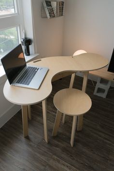 a laptop computer sitting on top of a wooden table next to two chairs in front of a window