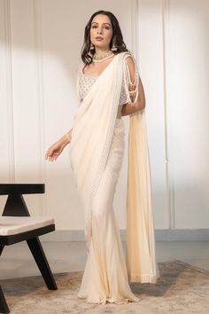 Ivory pre-draped saree with embellished border using crystal, sequins and mirror work. Paired with a blouse with all over crystal, mirror embellishments.
Components: 2
Pattern: Embellished
Type Of Work: Crystals, Mirror, Sequins
Neckline: V Neck
Sleeve Type: Sleeveless
Fabric: Blouse: Net, Saree: Georgette
Color: Ivory
Other Details: 
Length:
Blouse: 14 inches
Saree: 42 inches
Occasion: Sangeet - Aza Fashions Traditional Georgette Pre-draped Saree With Pearl Embroidery, Glamorous Pre-draped Saree With Pearl Embroidery For Festive Occasions, Glamorous Pre-draped Saree With Pearl Embroidery, Glamorous Festive Pre-draped Saree With Pearl Embroidery, Embellished Georgette Pre-draped Saree, Traditional Pre-draped Saree With Pearl Embroidery For Evening, Wedding Embellished Pre-draped Saree In Chinon, Bollywood Designer Saree With Pearl Embroidery, Bollywood Style Pre-draped Saree With Pearl Embroidery For Reception