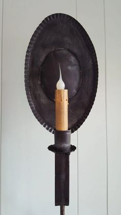 a candle is lit in front of a black plate on a stand with a wooden stick sticking out of it