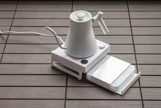 an electronic device sitting on top of a tile floor next to a white corded phone