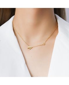 a woman wearing a gold necklace with an arrow charm on it's neck,