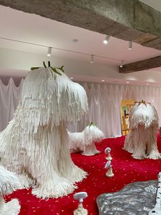 some very big furry white trees in the middle of a red carpeted room with curtains