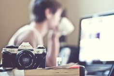 a camera sitting on top of a desk next to a laptop computer and a book