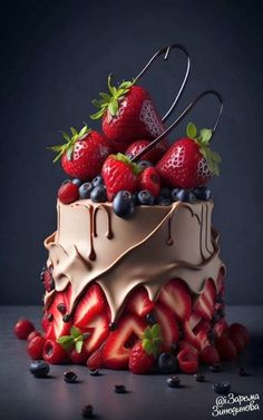 a chocolate cake with strawberries and blueberries on top is topped with icing