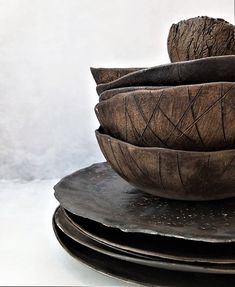 a stack of wooden bowls sitting on top of each other in front of a white wall