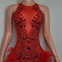 a mannequin wearing a red dress with sequins and feathers on it