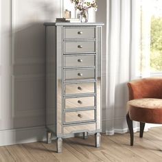 a silver chest of drawers sitting next to a chair