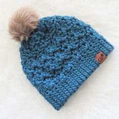 a blue crocheted beanie with a brown pom