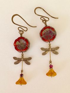 "Adorable red/orange Picasso Czech glass Hawaiian flowers with topaz bellflowers and vintage bronze stamped dragonfly charms. Red/orange 14 mm Czech flowers with rustic Picasso finish are wire wrapped in vintage bronze with 6 x 9 mm translucent topaz yellow bellflowers accented with tiny burnt orange crystals. Lightweight dangles hang on vintage bronze French ear wires. Total drop is 2 1/4\"." Vintage Orange Earrings With Czech Glass, Vintage Orange Czech Glass Earrings, Red Bohemian Soldered Earrings, Bohemian Red Soldered Earrings, Vintage Red Copper Earrings, Vintage Czech Glass Flower Earrings For Gift, Vintage Czech Glass Flower Earrings Gift, Red Whimsical Nickel-free Earrings, Whimsical Red Nickel-free Earrings