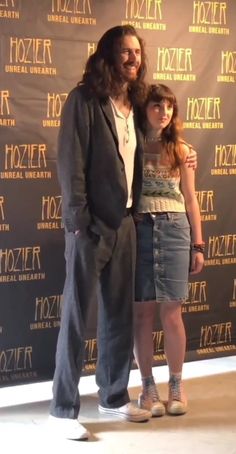 a man standing next to a woman in front of a wall with the words frozen on it