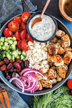 a bowl filled with chicken, vegetables and dressing