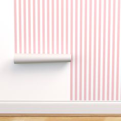 an empty roll of toilet paper sitting on the floor next to a pink striped wall