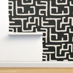 a black and white wallpaper with an abstract design on it's side, next to a wooden floor