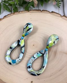 two pairs of scissors sitting on top of a piece of wood with flowers in the background