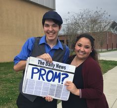 two people standing next to each other holding up a news paper with the word prom written on it