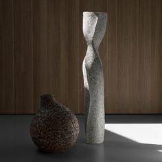 two vases sitting next to each other in front of a wooden wall and floor