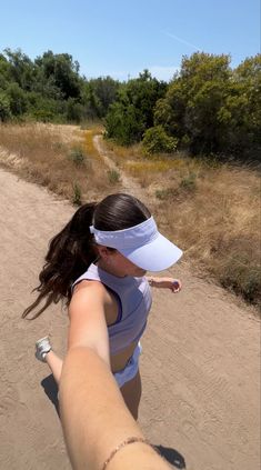 a woman is taking a selfie with her cell phone while walking down a dirt path