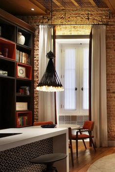 a living room filled with furniture next to a brick wall and window covered in curtains