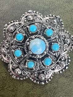 a silver brooch with blue stones on it