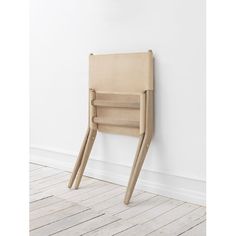 a wooden chair against a white wall