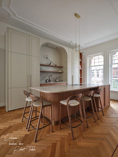 a large kitchen with wooden floors and white cabinetry, along with two bar stools