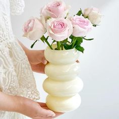 a person holding a vase with pink roses in it