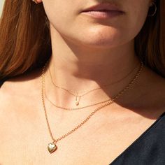 A woman with red hair and warm skin wears three gold chain necklaces. The choker has a tiny pearl charm and the longest necklace has a heart locket strung onto it. Everyday Fine Jewelry Paperclip Chain Necklace, Classic Gold Oval Link Diamond Necklace, Delicate 14k Gold Diamond Necklace With Cable Chain, Classic Charm Necklace With Delicate Chain For Everyday, Classic 14k Gold Charm Necklace With Cable Chain, Fine Jewelry Necklace With Oval Link, Dainty 14k Gold Chain Charm Necklace, Fine Jewelry Necklaces With Delicate Oval Link Chain, Everyday Gold Initial Pendant Diamond Necklace