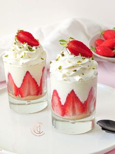 two desserts with strawberries and whipped cream are on a plate next to each other