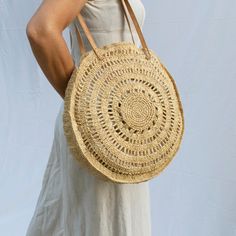 Beautifully woven large round bag made from natural raffia with leather shoulder straps. The perfect bag for any summer adventures and folds flat so is ideal for packing away for your next holiday escape. Dimensions o      Circumference 39cm/15'',  Depth 8cm/3'' oStrap Drop 33cm/13'' All bags are handmade so may vary slightly in size. All our raffia hats and bags are designed by us and woven by our amazing artisan partners in Madagascar.  As a business our philosophy is to produce fair trade, hi Everyday Natural Straw Bag With Round Handle, Bohemian Straw Bag With Round Handle For Daily Use, Natural Color Beach Bag With Round Handle, Round Vacation Bags, Bohemian Everyday Straw Bag, Natural Bucket Bag With Round Handle For Beach, Bohemian Palm Leaf Straw Bag For Everyday, Natural Crochet Bag With Round Handle For Daily Use, Round Straw Beach Bag For Summer