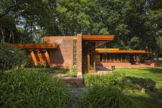 the exterior of a brick house surrounded by greenery