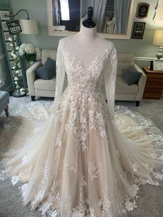 a wedding dress on display in a room with a white couch and mirror behind it