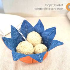 two balls of yarn are in a blue and orange flower shaped bowl with crochet needles