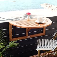 a wooden table sitting on top of a balcony next to a chair and potted plant