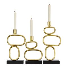 three gold metal candlesticks with one candle in the middle and two on each side