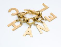 Chanel Letter Charm Bracelet Iconic and rare Chanel gold plated letter charm bracelet from Spring 1993 Collection. Chain link bracelet features toggle clasp. Comes with box. Approximate Measurements: Length 7.5”, Width 2.8” Made in: France.Thanks for viewing this item: we have more Chanel jewelry here. To find out more about Chanel's history please visit our blog. Formal Yellow Gold Jewelry With Gold-tone Logo Lettering, Designer Yellow Gold Jewelry With Logo Lettering, Luxury Gold-tone Jewelry With Logo Lettering, Modern Gift Jewelry With Gold-tone Logo Plaque, Modern Jewelry With Gold-tone Logo Plaque As Gift, Designer Gold Bracelets With Logo Charm, Designer Gold-tone Logo Bracelets As Gift, Gold Jewelry With Logo Charm For Collectors, Gold-tone Formal Bracelets With Logo Charm